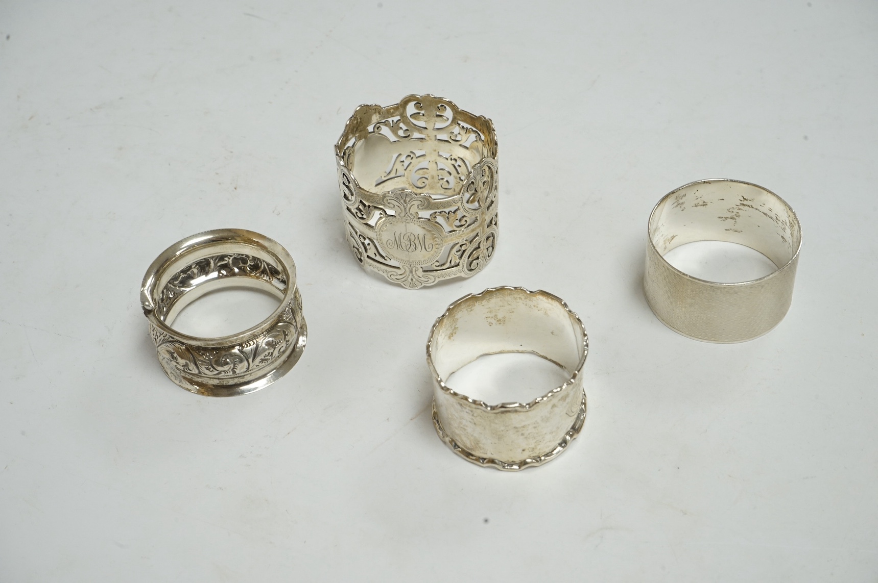 Four assorted silver napkin rings, including pierced by Josiah Williams & Co, London, 1899. Condition - poor to fair